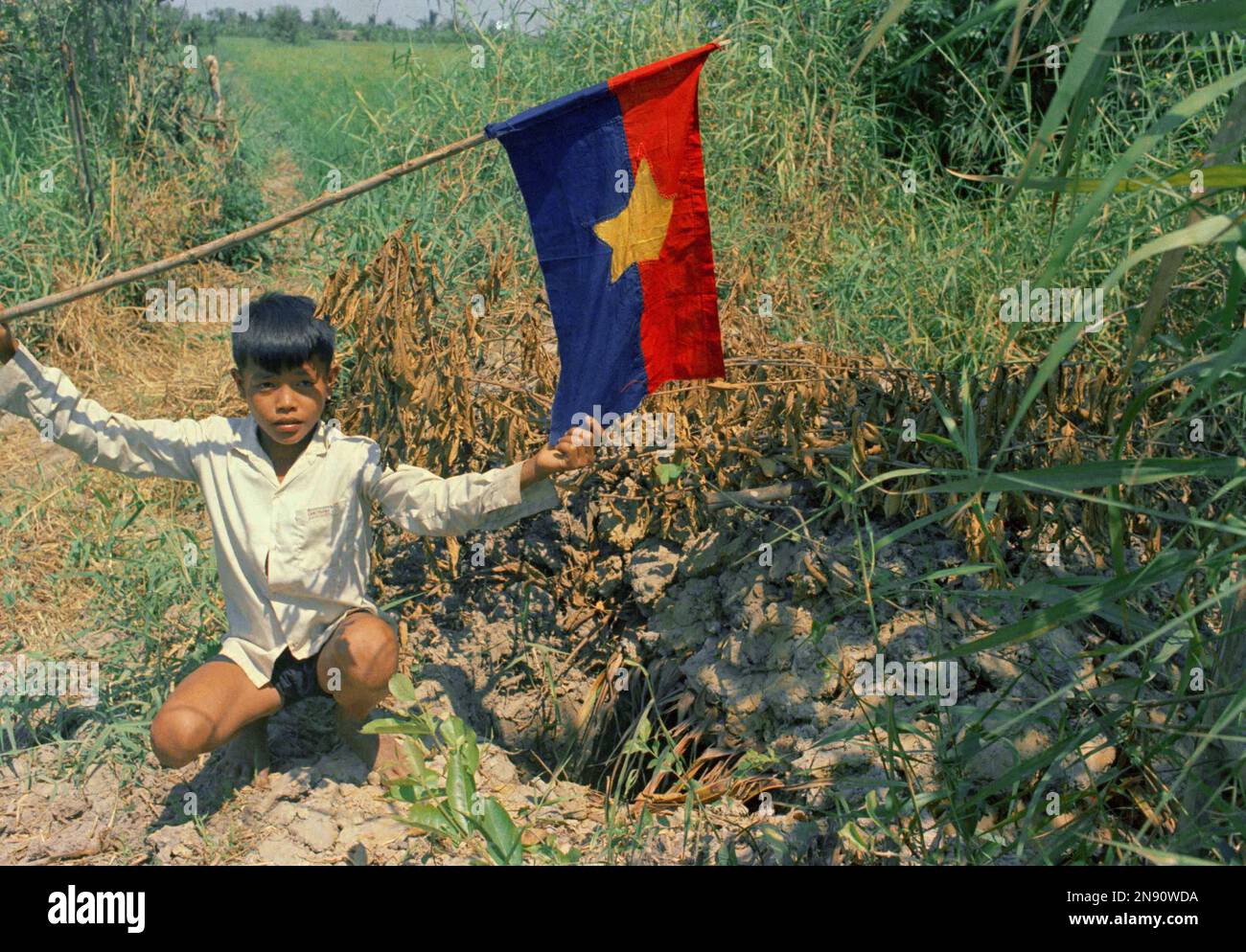 A Vietnamese boy poses with a Vietcong flag at Bien Phong Hamlet
