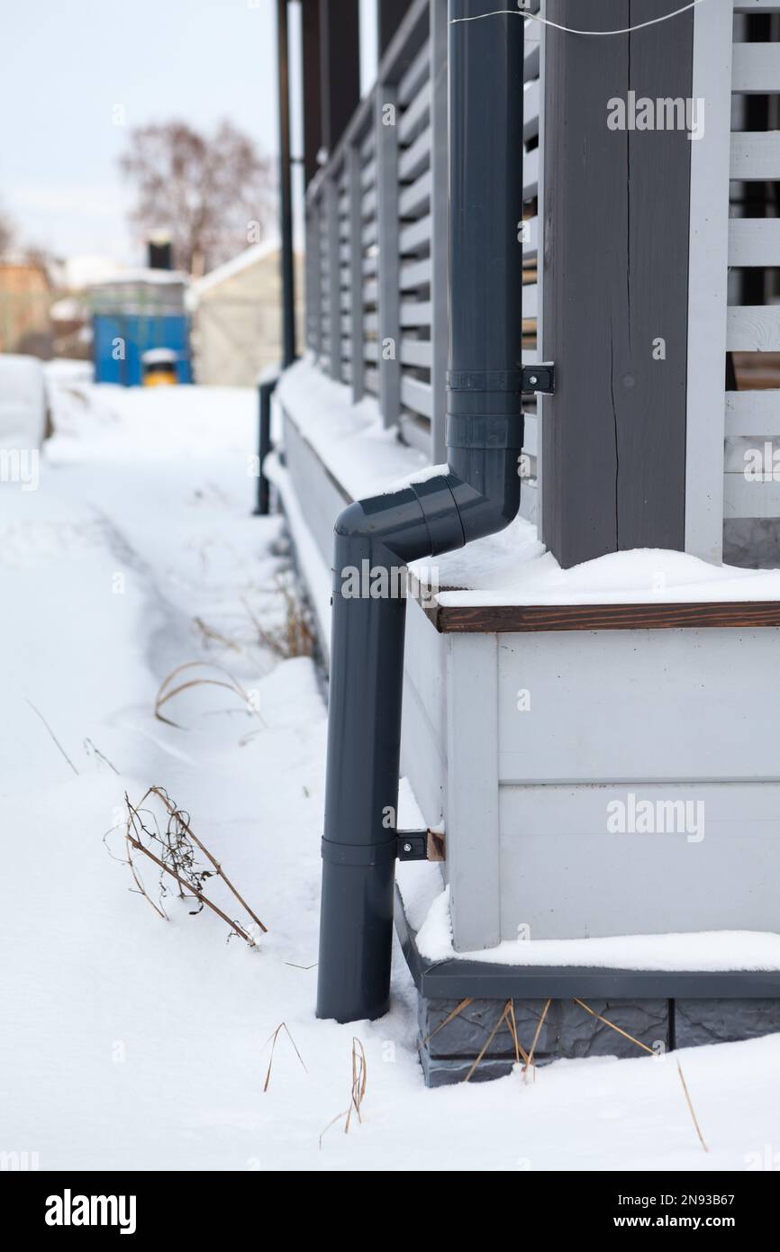 Downspout plastic pipe for a wooden porch of a cottage, frozen and