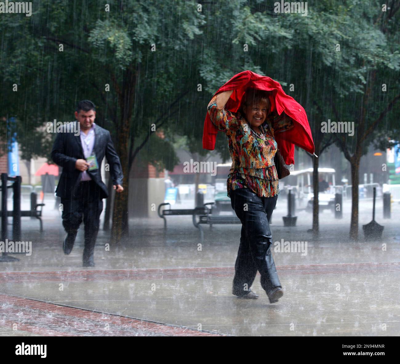 Delegates run for shelter in a downpour as they arrive at the