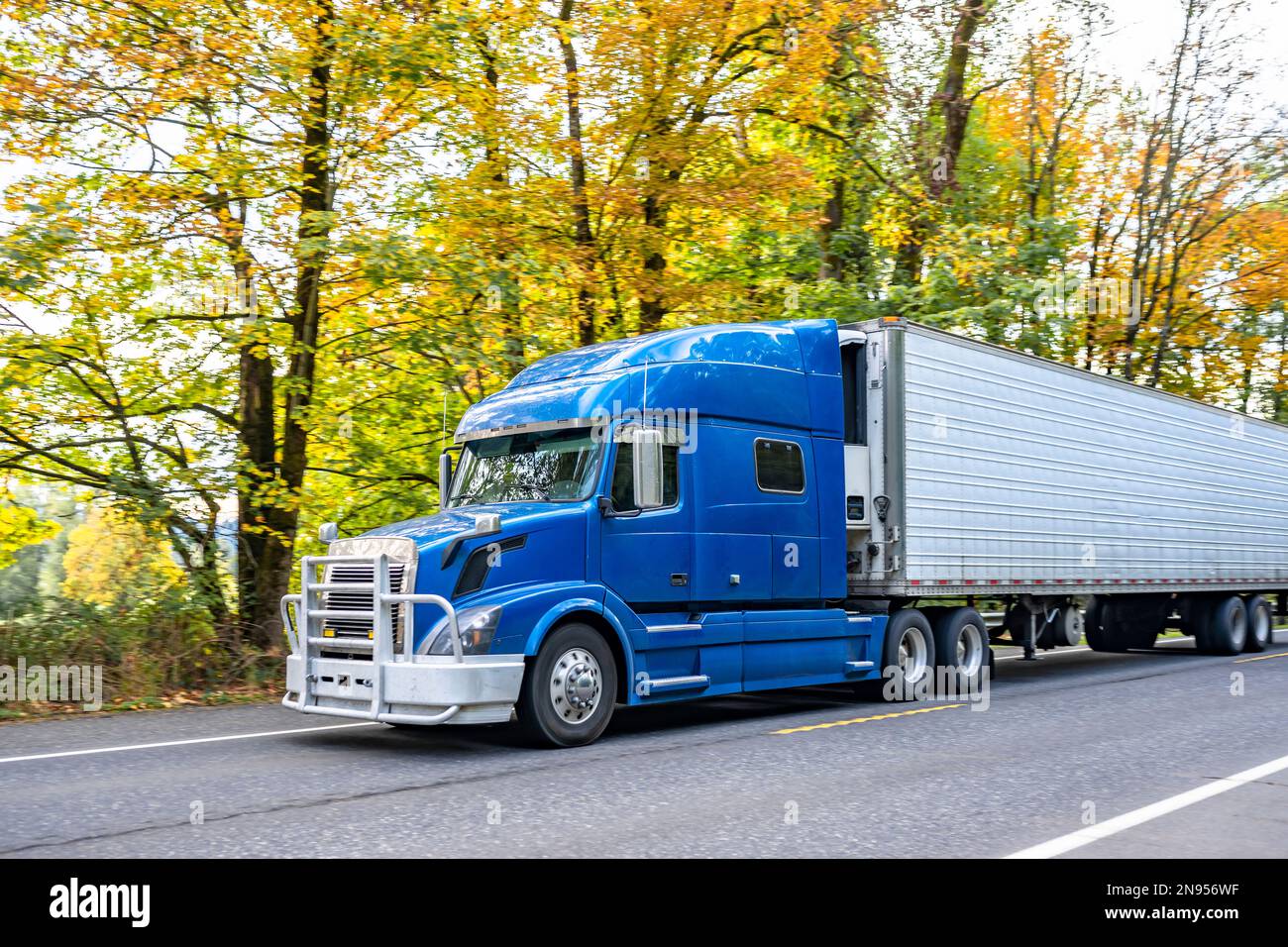 Industrial Long hauler big rig blue semi truck tractor with extended cab for truck driver rest transporting frozen cargo in refrigerator semi trailer Stock Photo