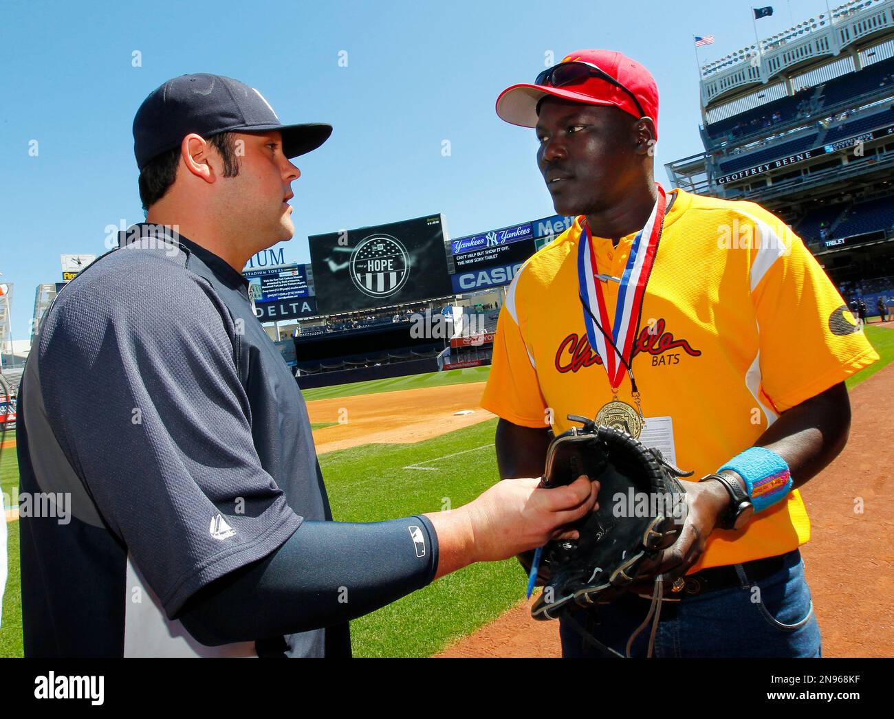 New York Yankees pitcher Joba Chamberlain, left, presents Odong Henry,  manager of the Little League baseball team from Uganda, with a glove on the  field before the start of of a baseball