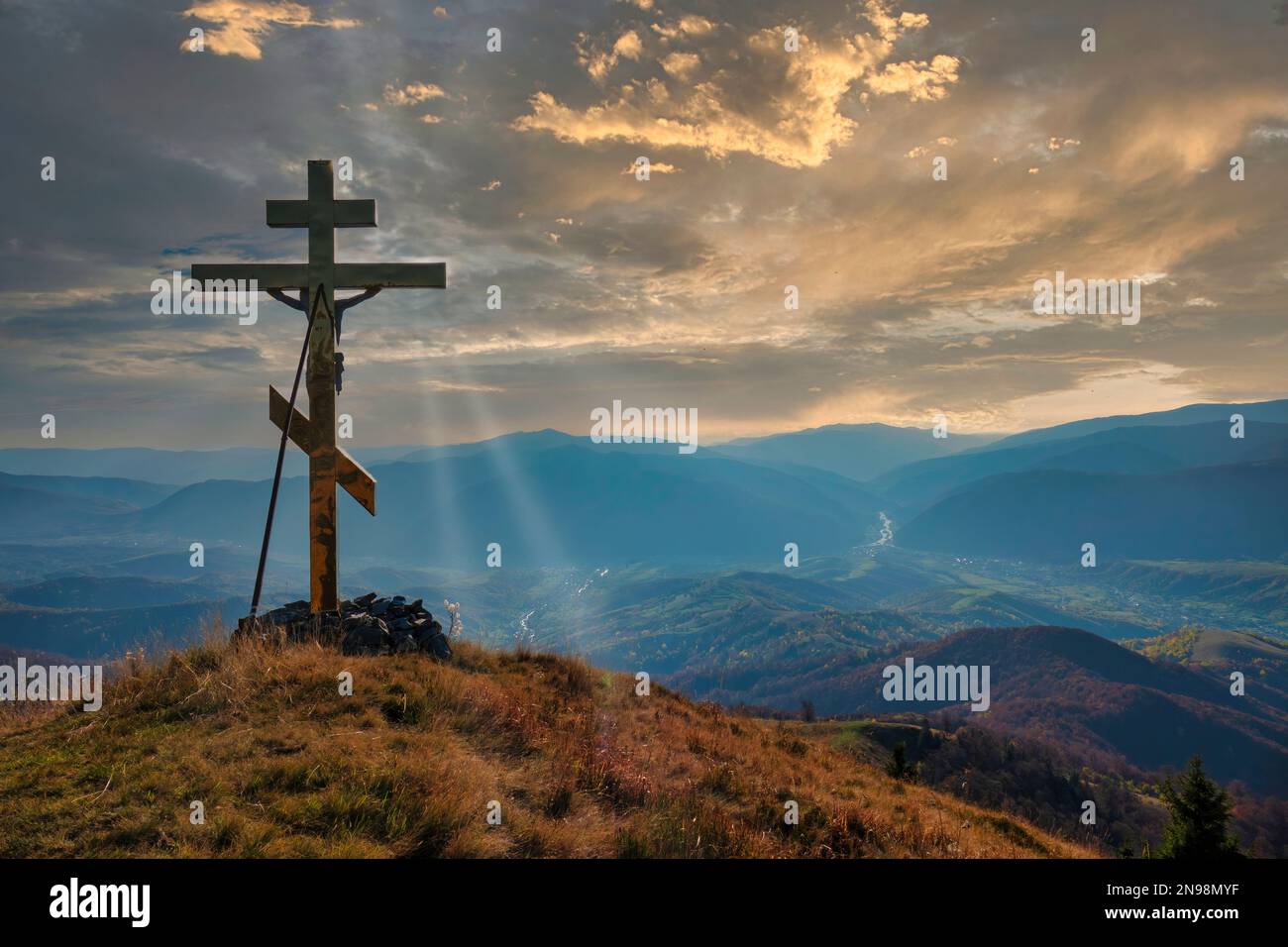 Christian cross on the mountain top at the sunset. Symbol of Christianity and Saviour Stock Photo