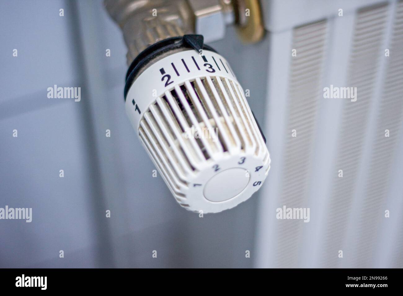 white Heating radiator with regulator to save energy in crisis and radiator with selective focus on thermostat Stock Photo