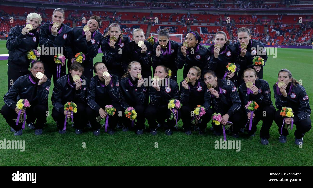 United States soccer players kiss their gold medals while posing for