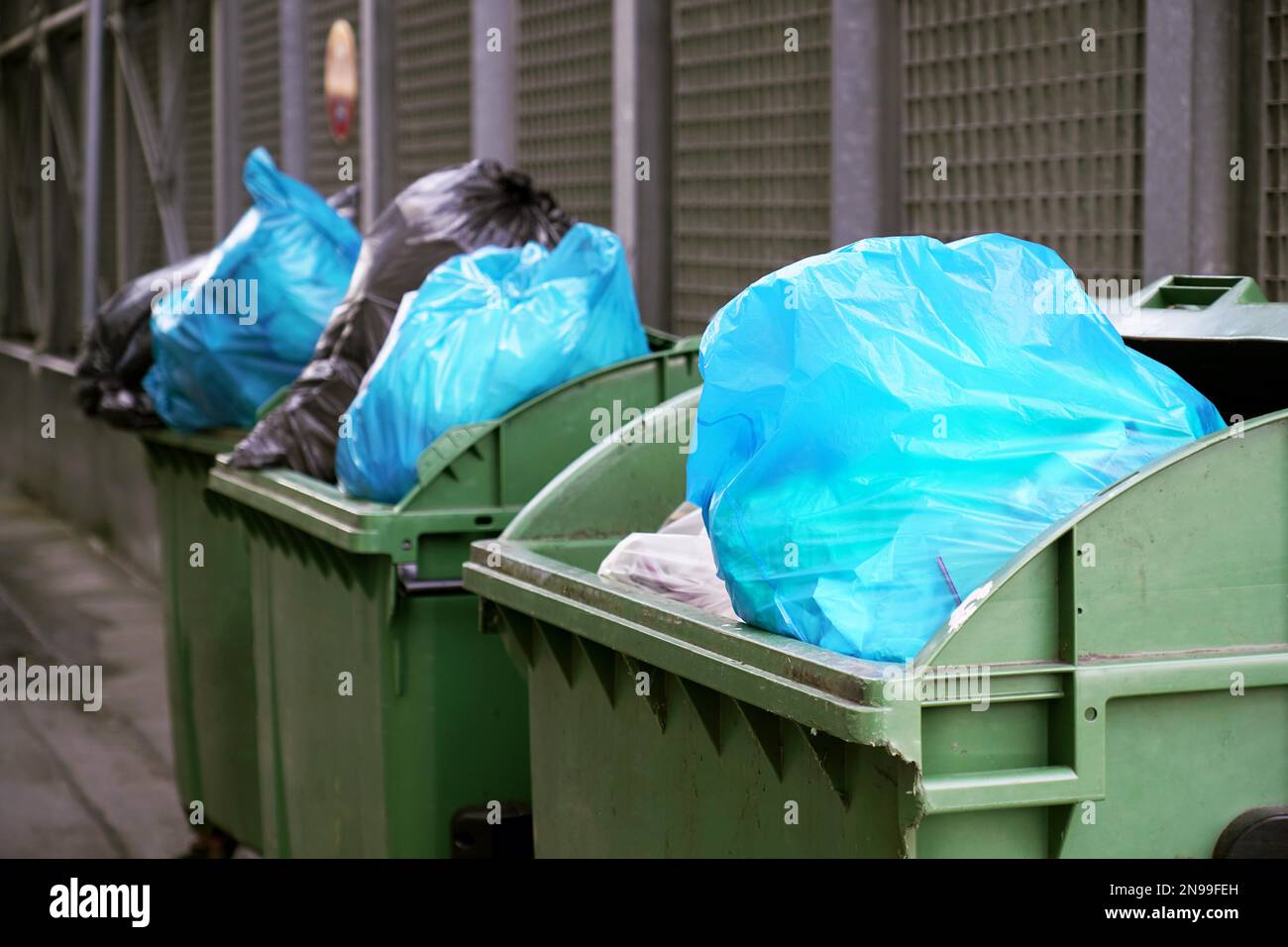 dumpster or refuse container overflowing with trash in garbage bags in