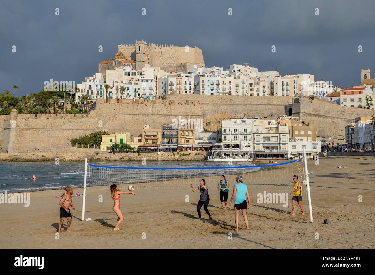 Beach volleyball players on the beach of Peniscola, in the background