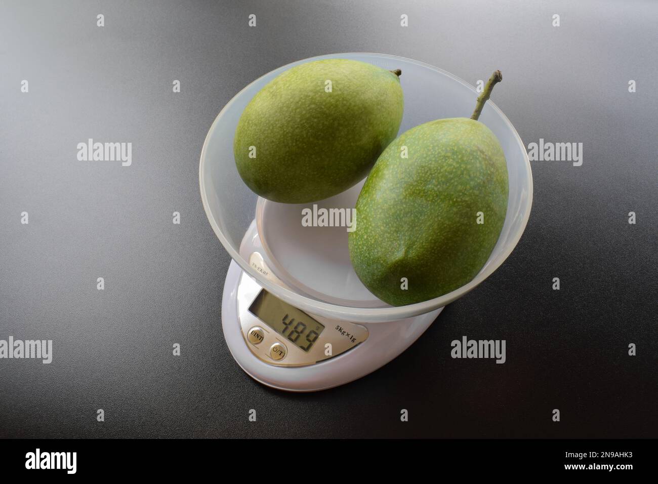 Mango fruit on digital kitchen scales isolated on black background Stock Photo