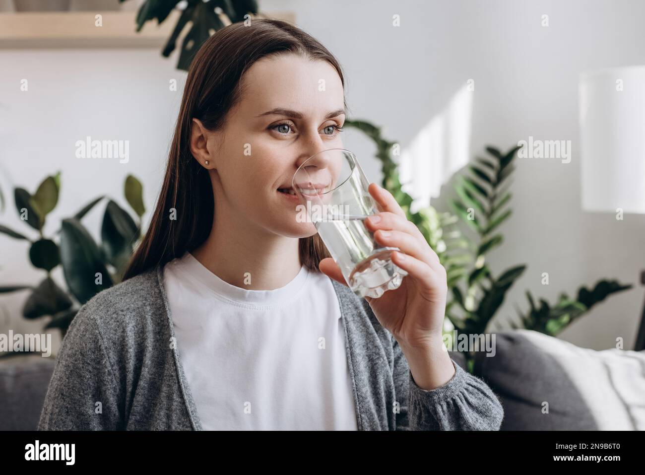 Smiling beautiful peaceful young pregnant female drinking glass of