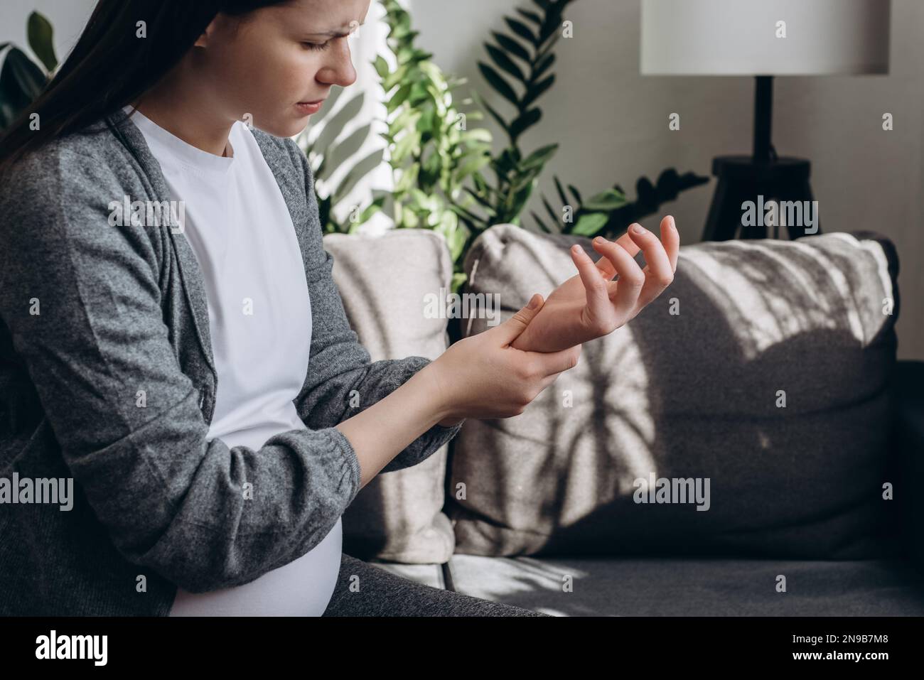 Selective focus of sad pregnant woman suffering pain on hands and fingers, arthritis