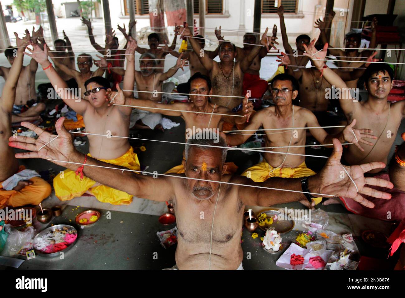 Indian Hindu priests perform rituals holding sacred threads during a ...