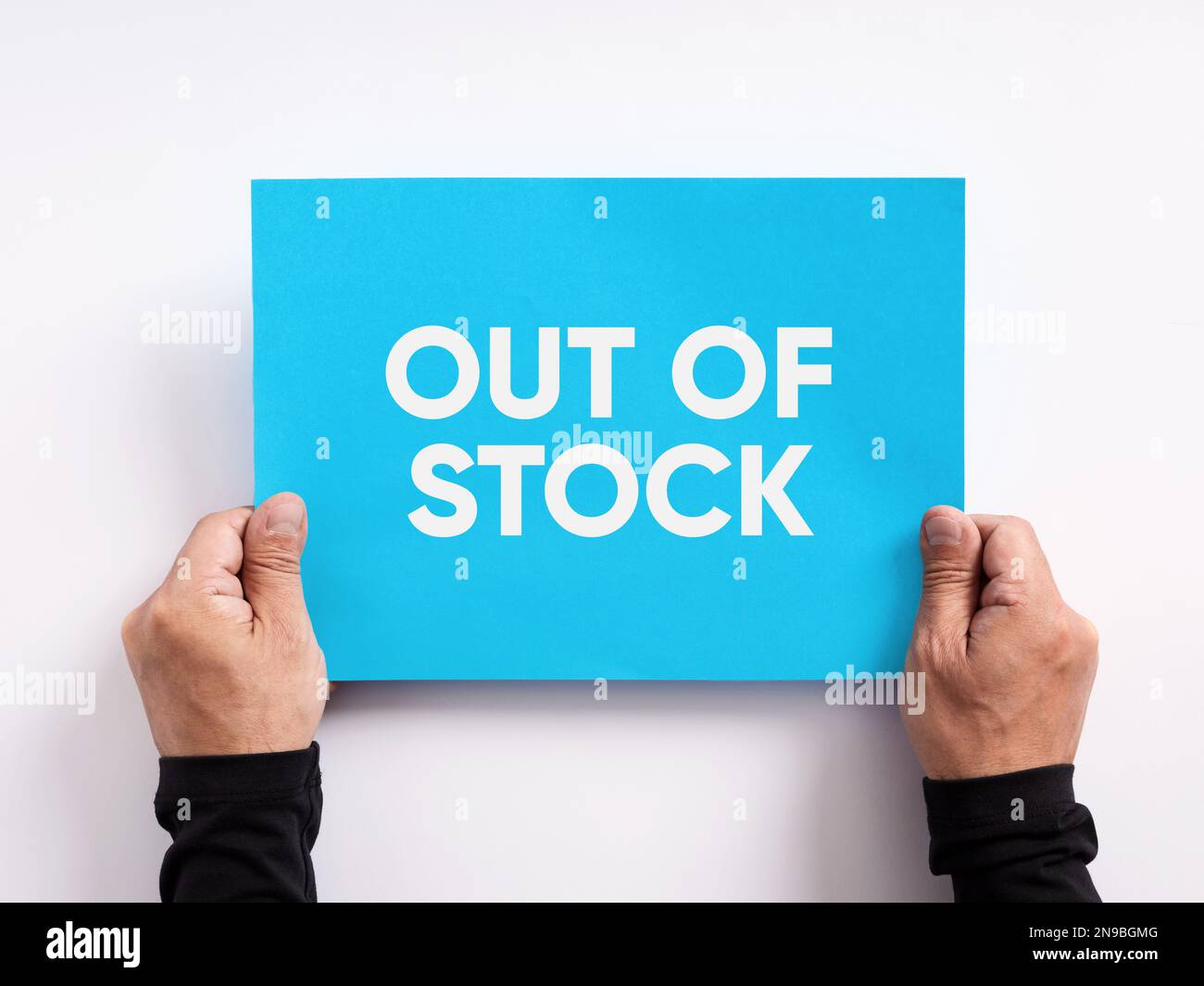 Male hand holding a blue paper with the message out of stock. Stock Photo