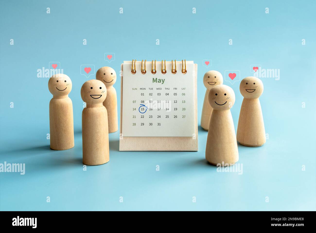International Family Day concept. Circle mark on date May 15, 2023, on May month page desk calendar near happy smiling wooden figures, people with lov Stock Photo