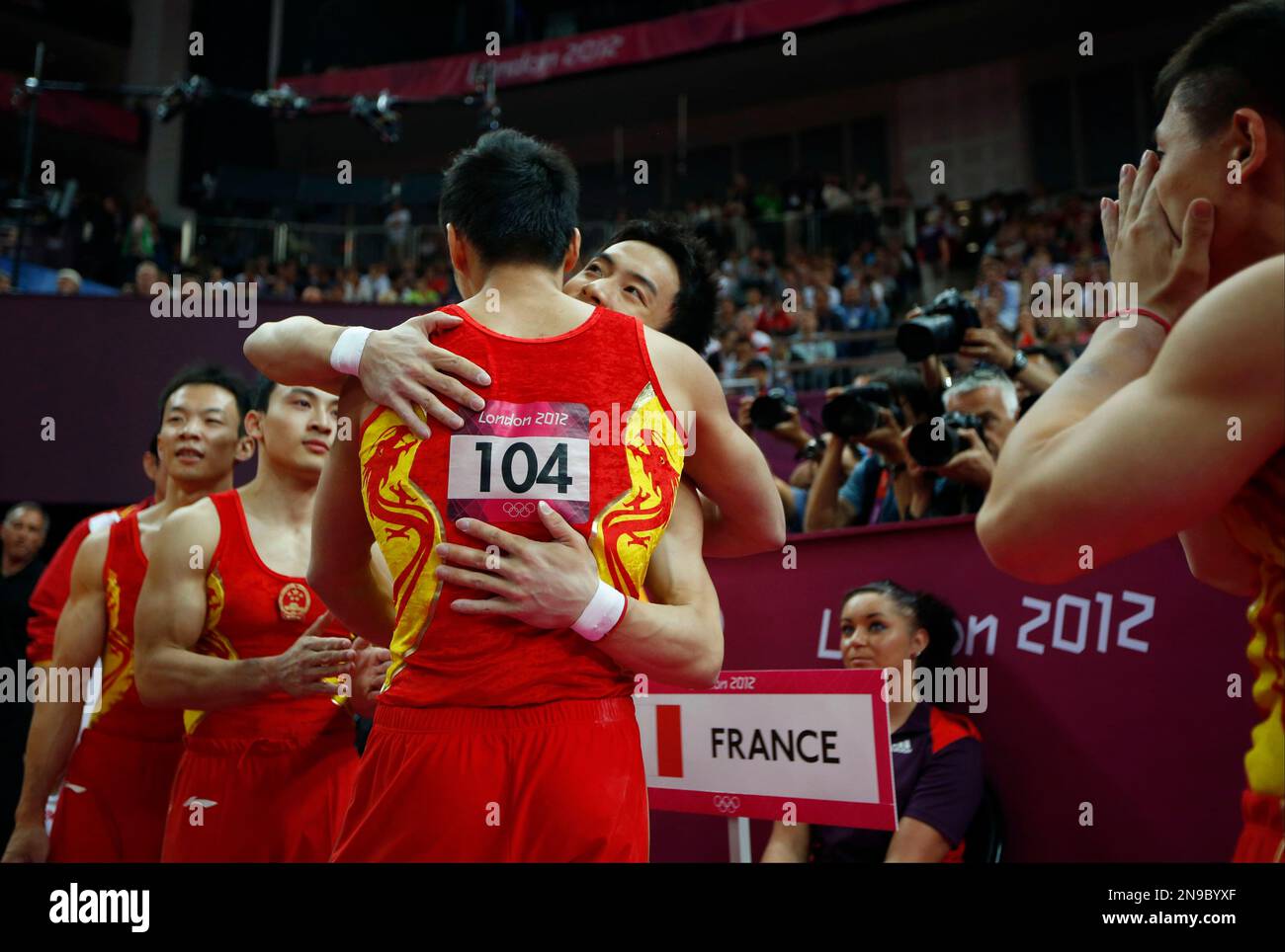 Chinese gymnasts celebrate as results are displayed on the screen announcing them as winners of