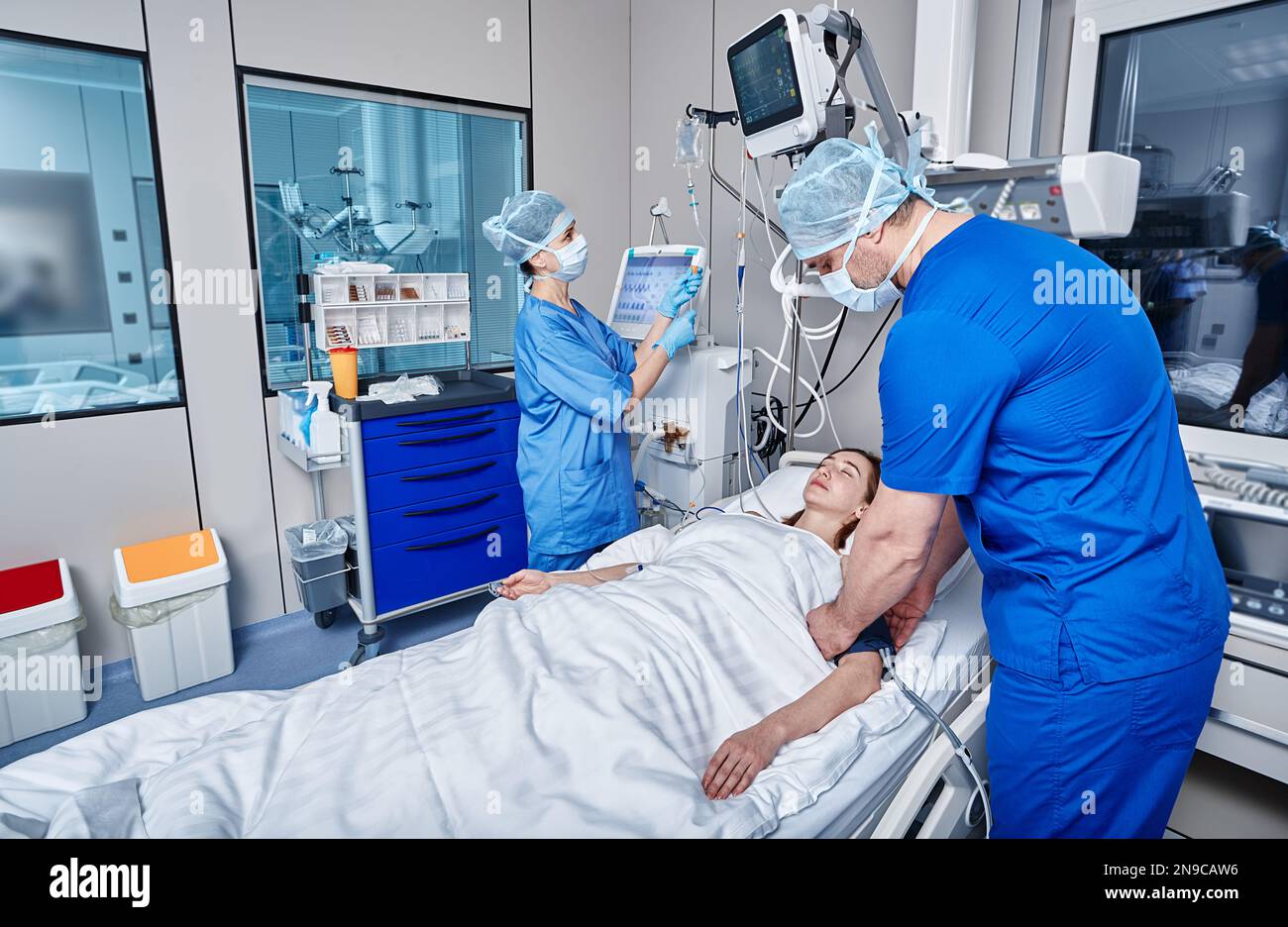 Staff nurses attending to patient in adult intensive care unit. ICU