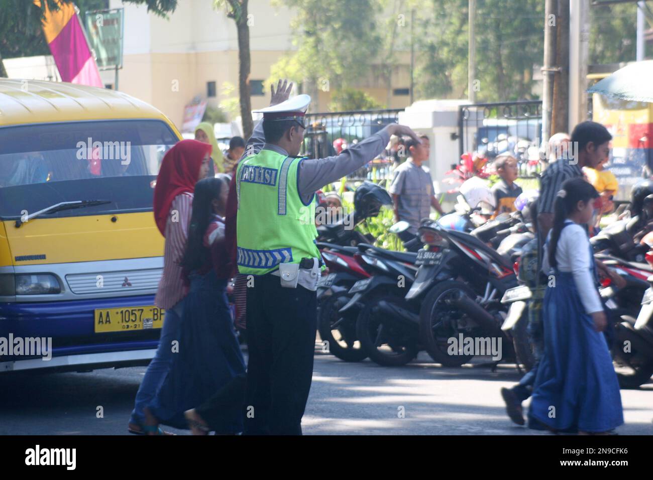 a traffic cop in indonesia who is helping people cross the road Stock Photo