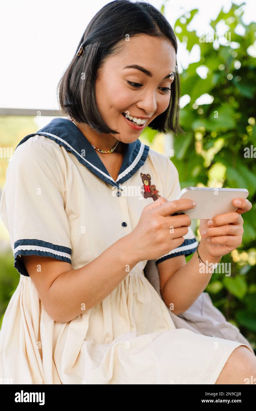 Young beautiful cheerful asian girl wearing dress playing game on ...