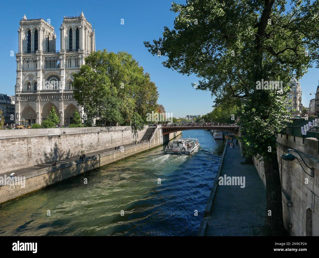 Notre-Dame cathedral seen from La Seine with a cruise boat in Paris France on a sunny day Stock Photo