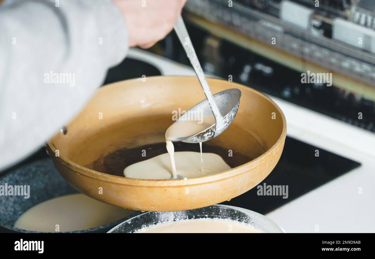 Russia Moscow 14.03.2021 Cooking many big tasty pancakes Lot of pans,oil,pancake dough.Russian traditional national festival winter Maslenitsa holiday Stock Photo