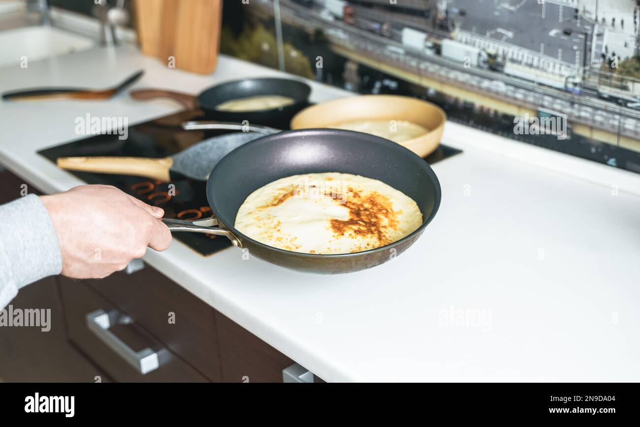 Russia Moscow 14.03.2021 Cooking many big tasty pancakes Lot of pans,oil,pancake dough.Russian traditional national festival winter Maslenitsa holiday Stock Photo