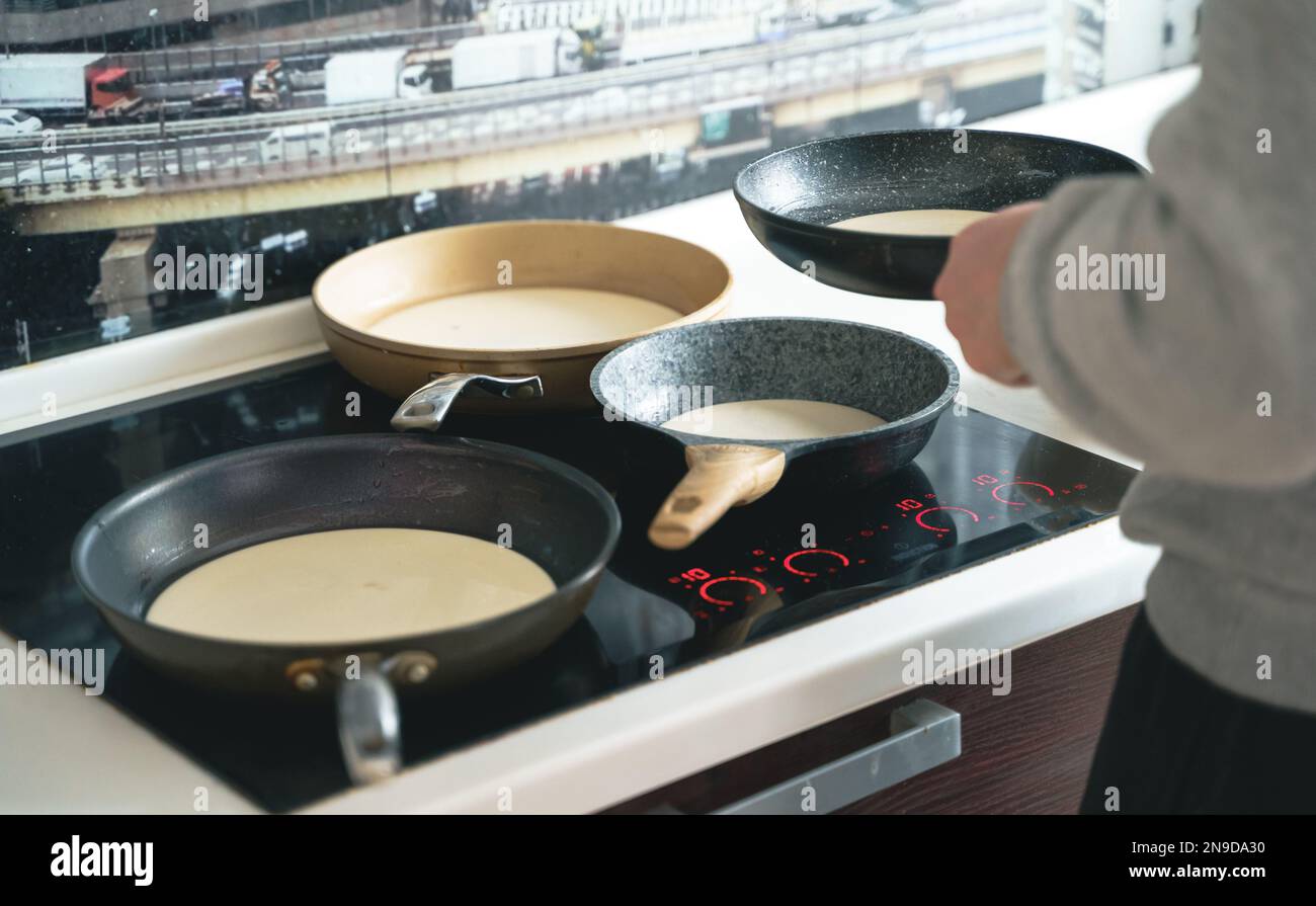 Russia Moscow 14.03.2021 Cooking many big tasty pancakes Lot of pans,oil,pancake dough.Russian traditional national festival winter Maslenitsa holiday Stock Photo