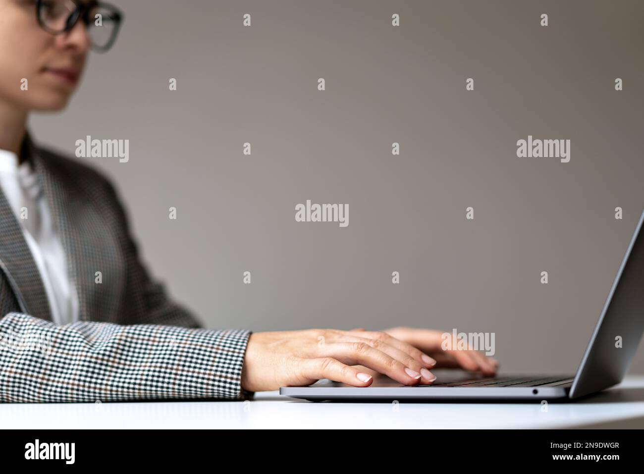 Business woman in glasses sitting at the desk in office using laptop. Template working on laptop. Stock Photo