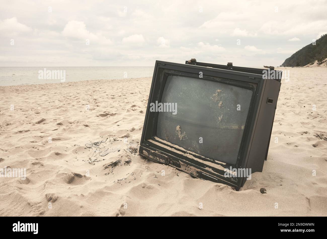 Old broken TV set on a beach, color toning applied. Stock Photo