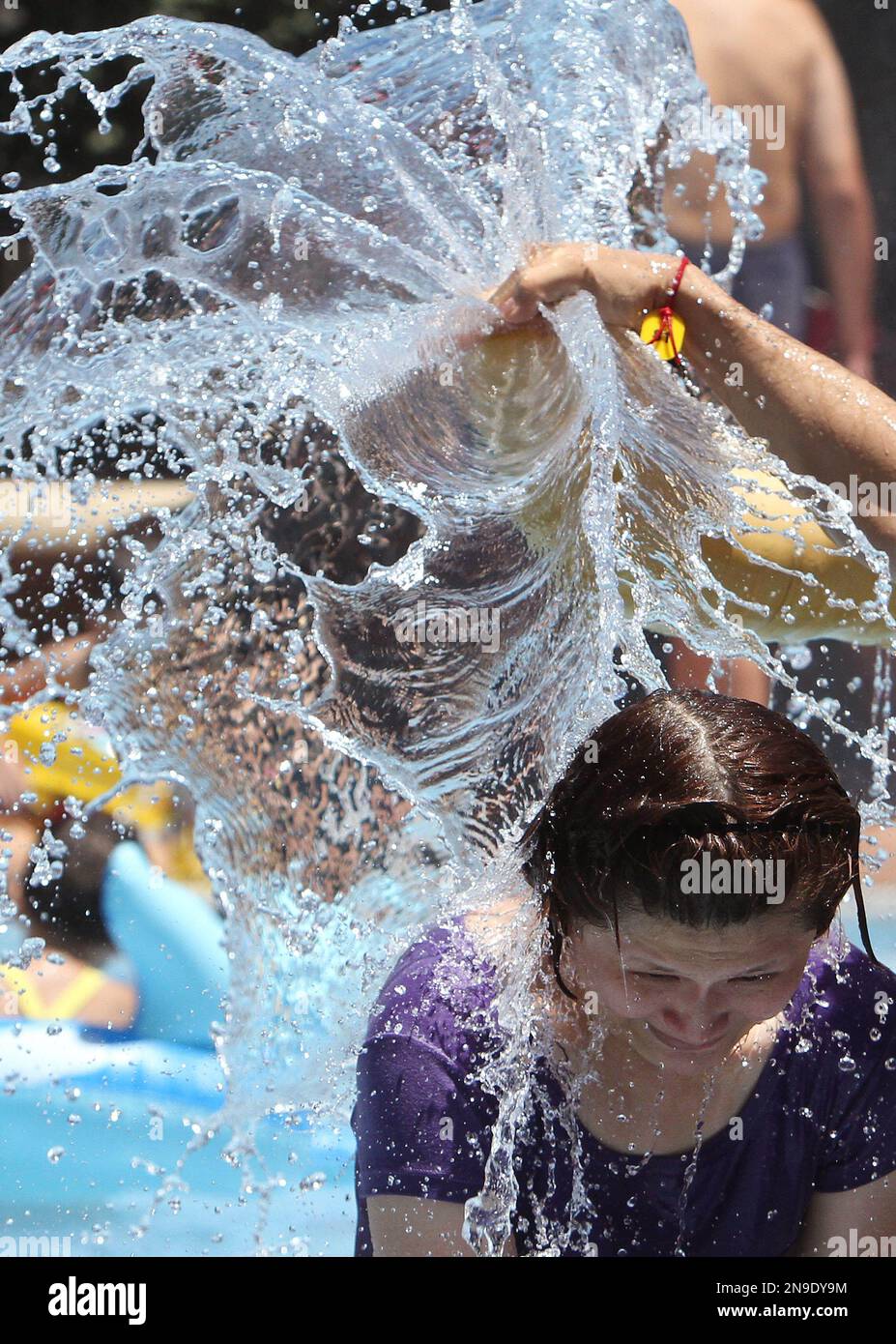 A Taiwanese woman on a water slide gets a splash of water to cool down ...