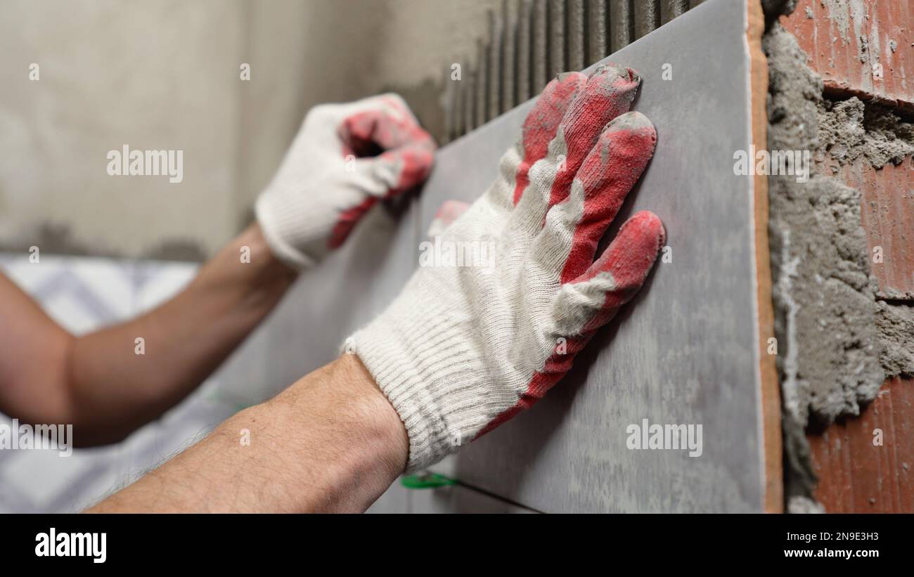 Instaling ceramic tiles. Male hands glue ceramic tiles on the wall in ...
