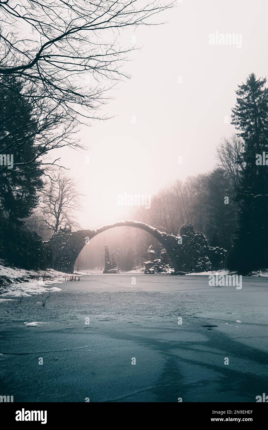 Middle Earth in Winter: An Old Stone Bridge over a Frozen Lake Stock Photo