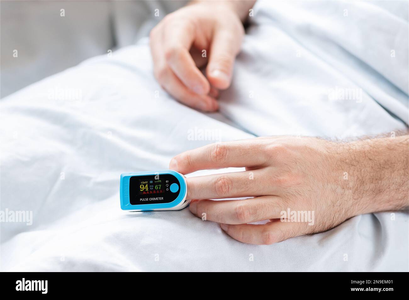 Patient lying at bed with pulse oximeter. Close up of hands. Concept of