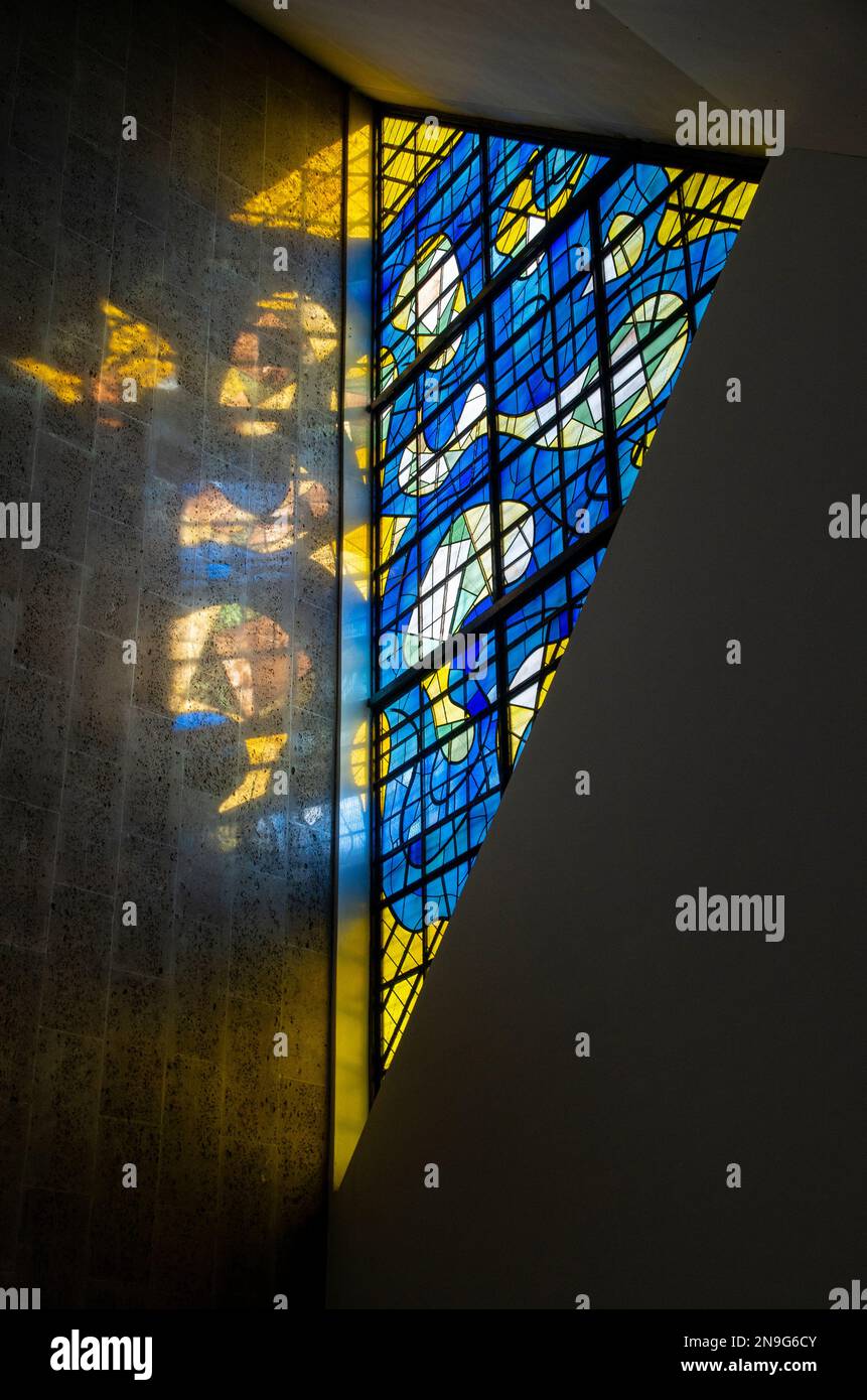 Sunlight streams through a modern, abstract, stained glass window at
