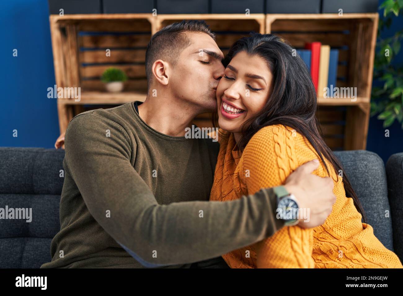 Man and woman couple kissing and hugging each other sitting on sofa at ...