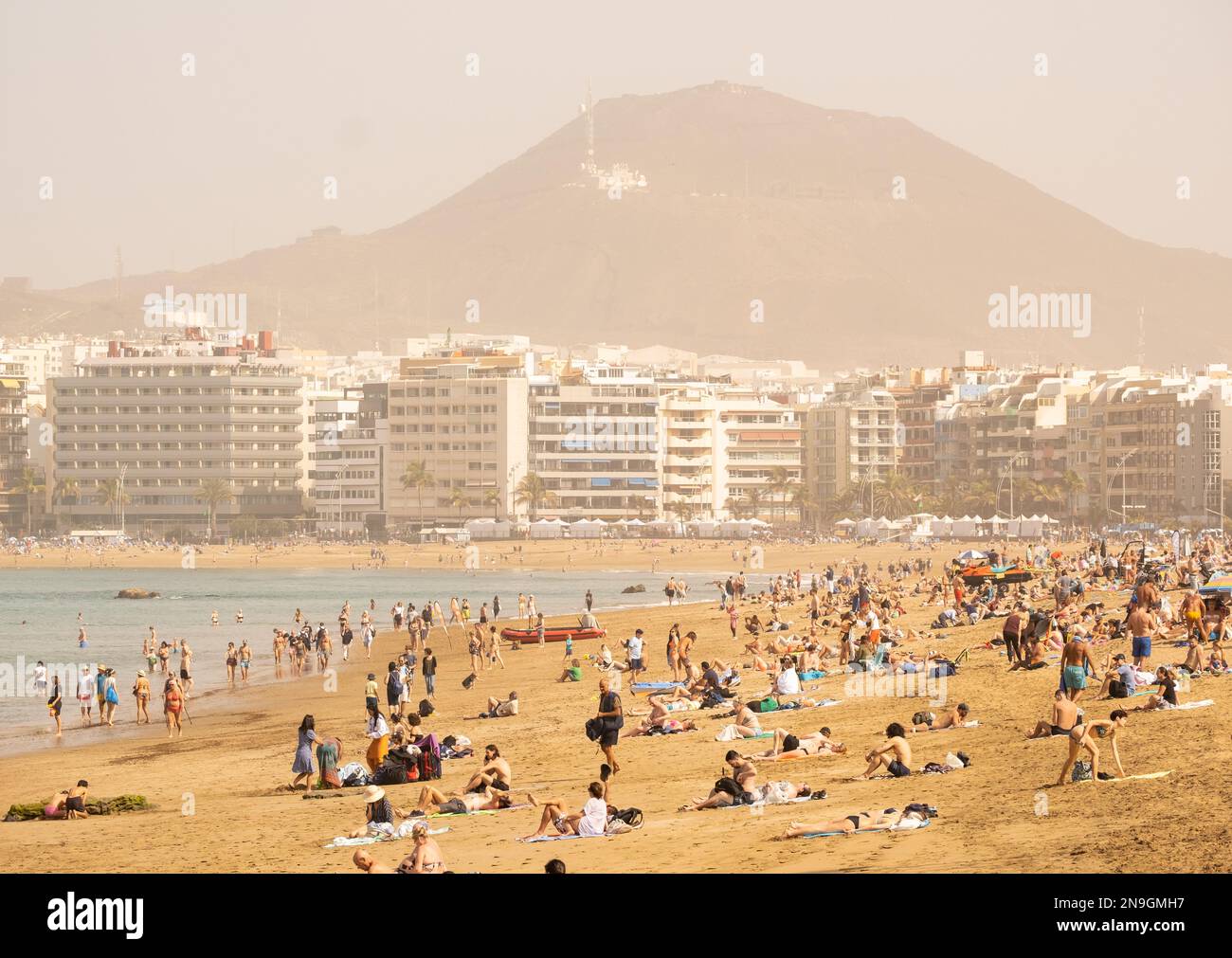 Las Palmas, Gran Canaria, Canary Islands, Spain. 12th February 2023.  Tourists, many from the UK, keep cool on the city beach in Las Palmas as  Saharan sand and dust blows in from