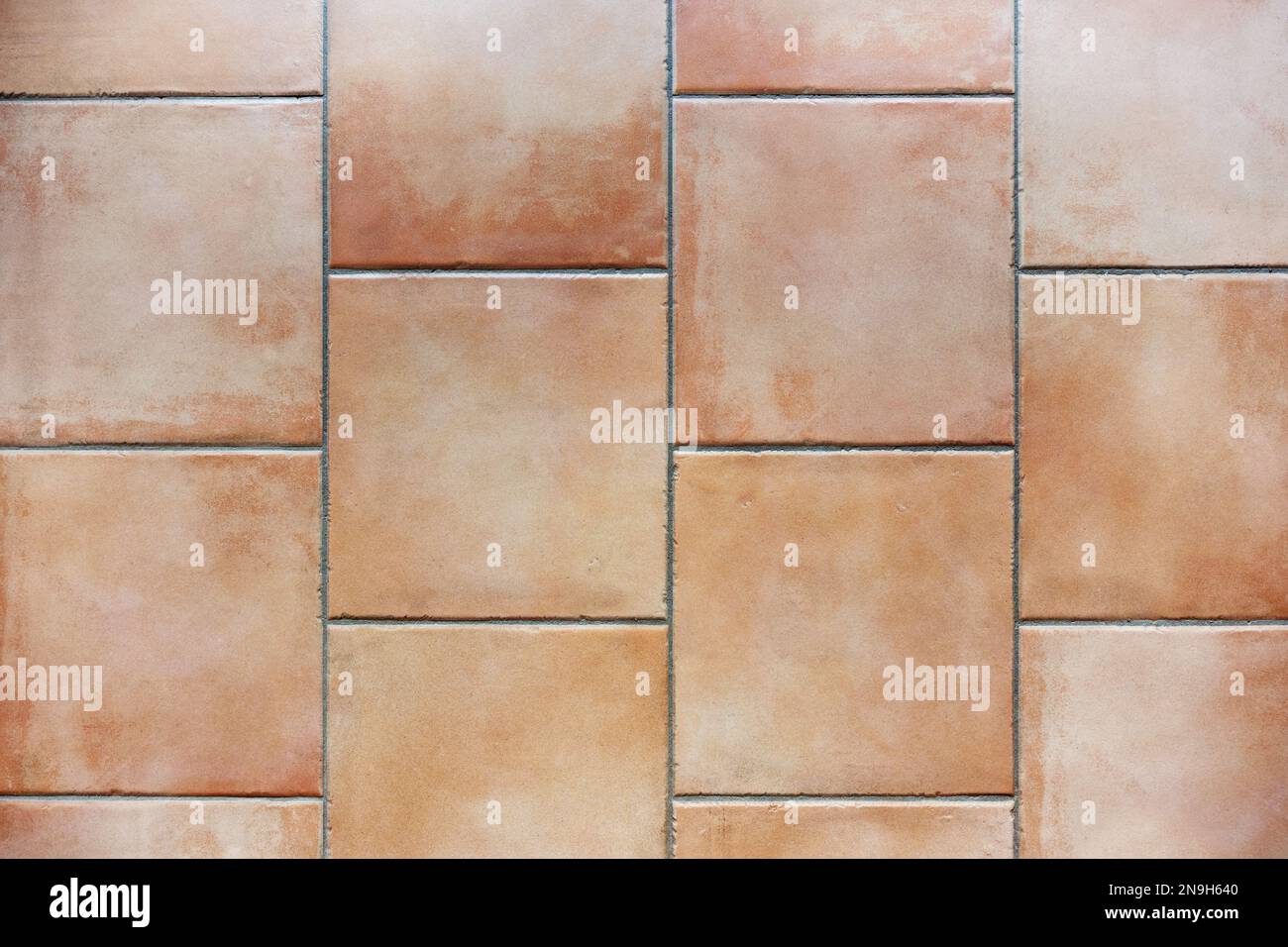 Tiled floor with natural terracotta ceramic tiles and gray grout, background texture, indoor architecture concept, copy space, high angle view from ab Stock Photo