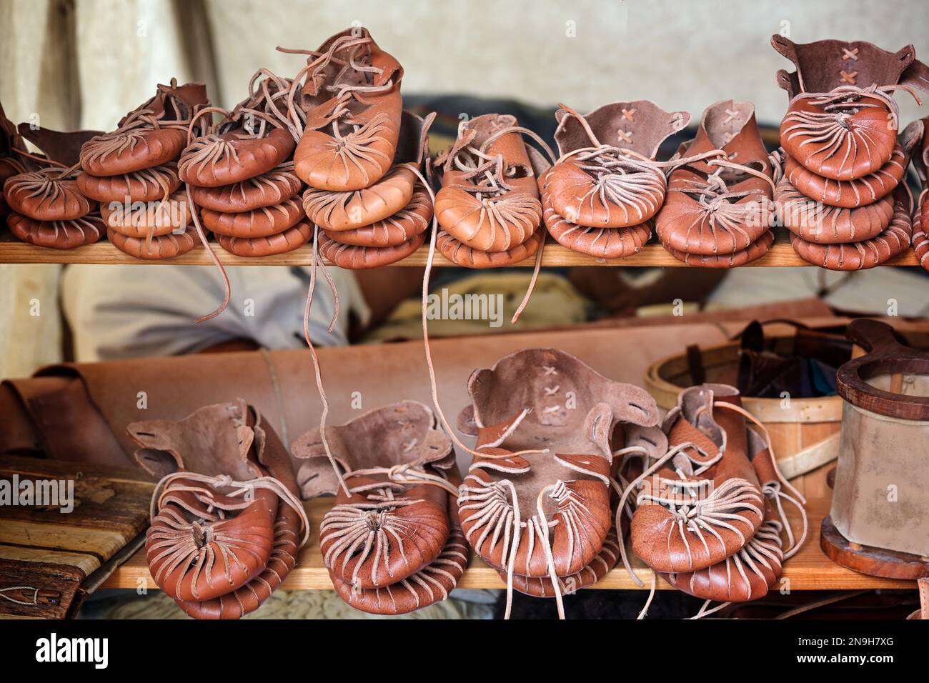 Handmade historical leather shoes for sale stacked on shelves at a medieval market, copy space, selected focus, narrow depth of field Stock Photo