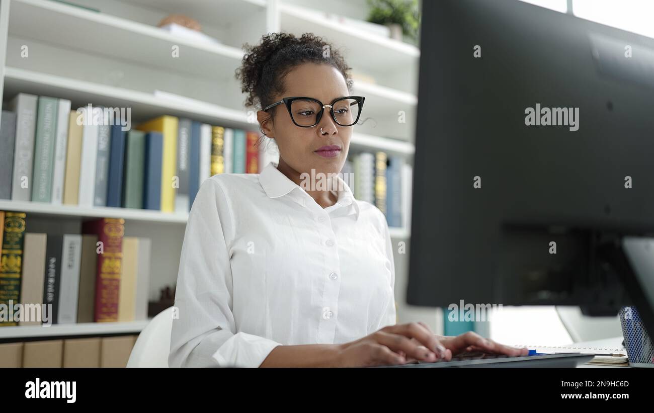 African american woman student using computer studying at library ...