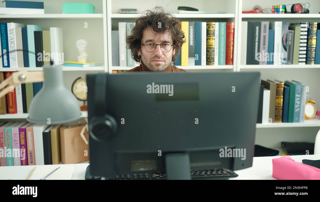 Young hispanic man student using computer studying at library ...