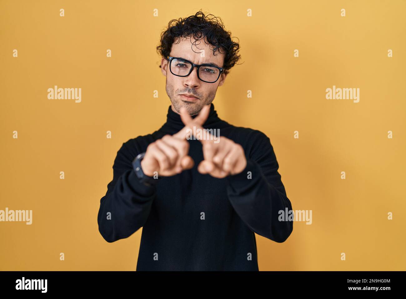 Hispanic man standing over yellow background rejection expression ...