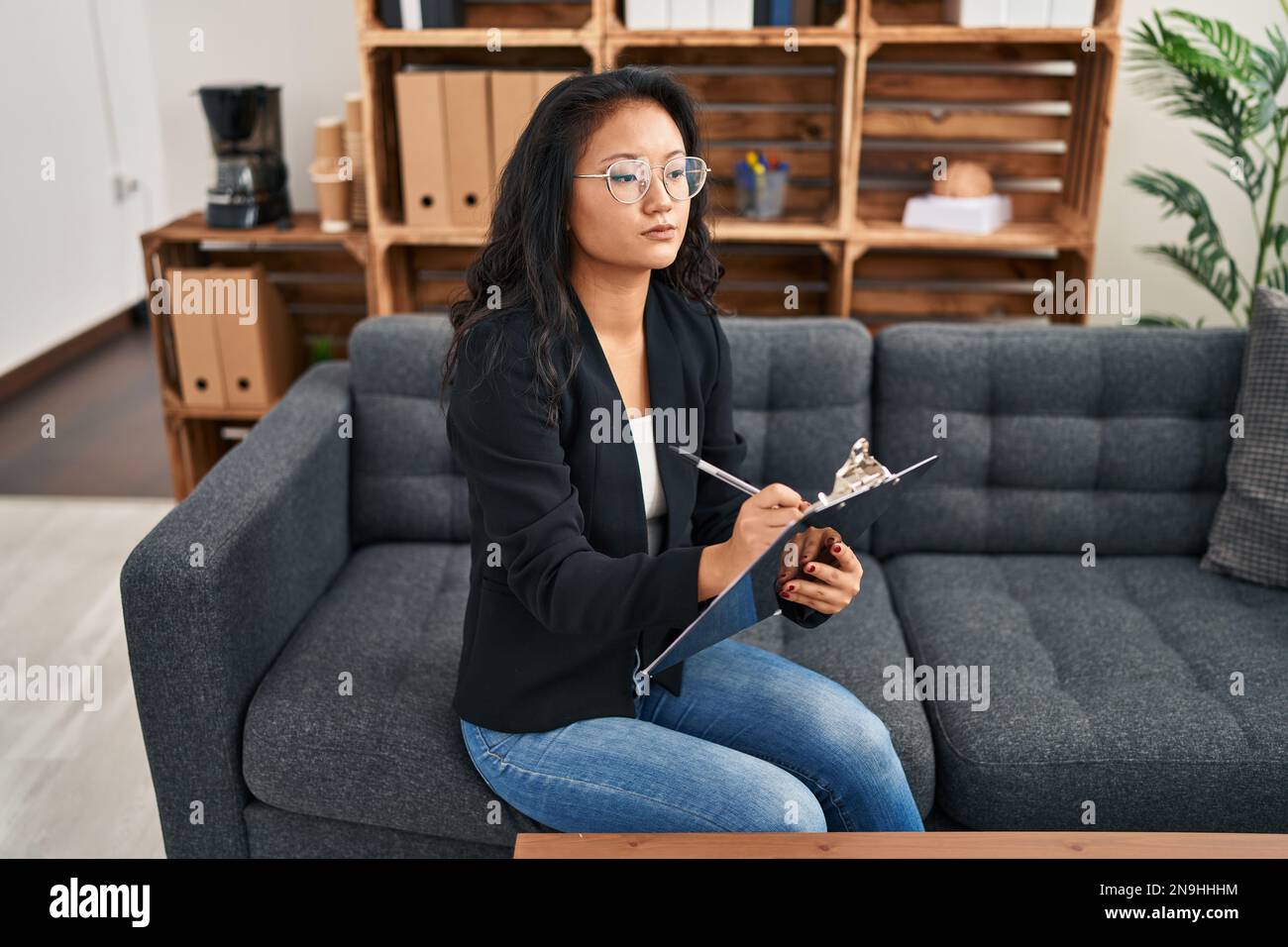 Young chinese woman psychologist writing on clipboard at clinic Stock Photo Alamy
