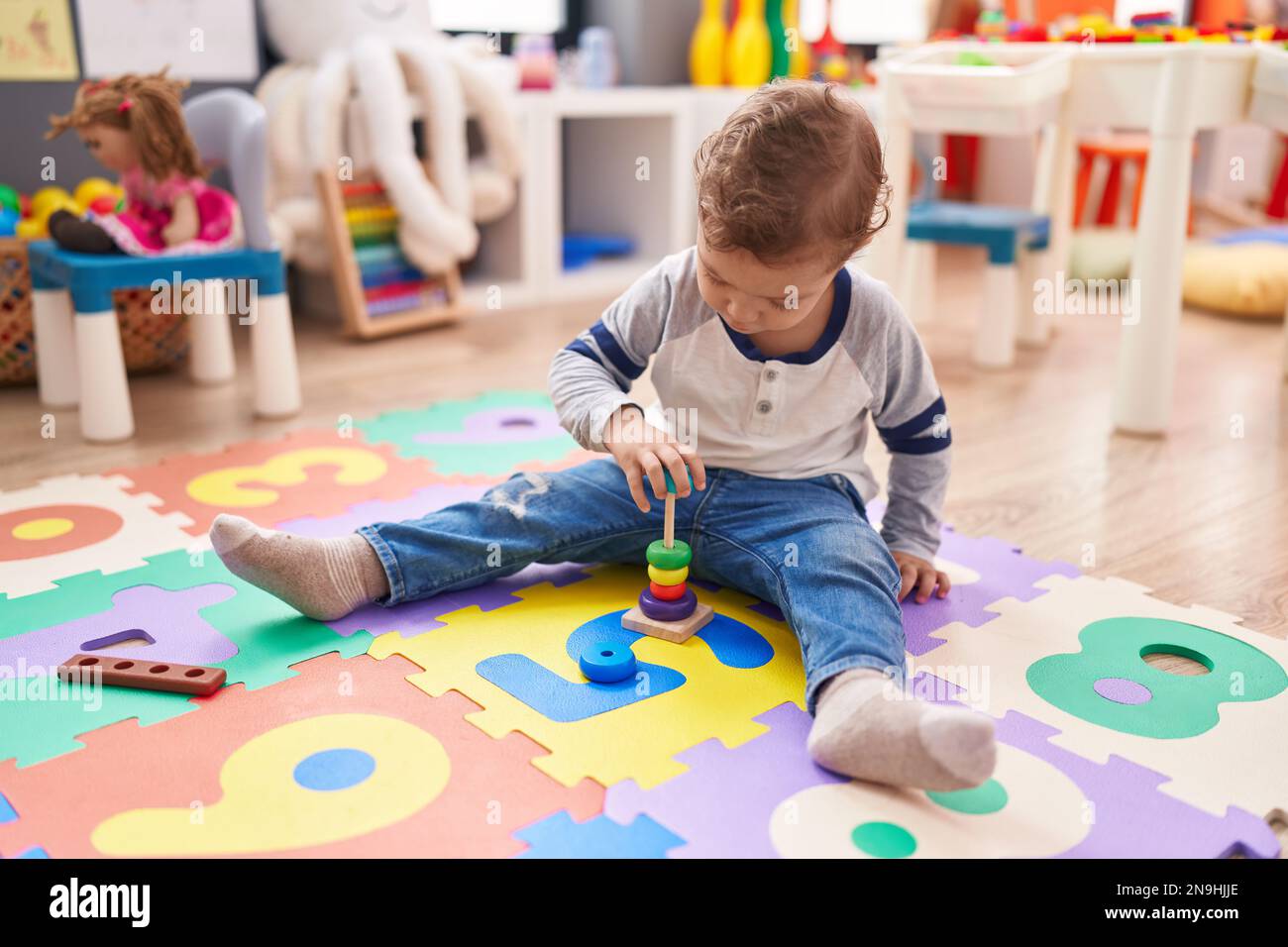 Adorable caucasian boy playing with hoops toy sitting on floor at ...