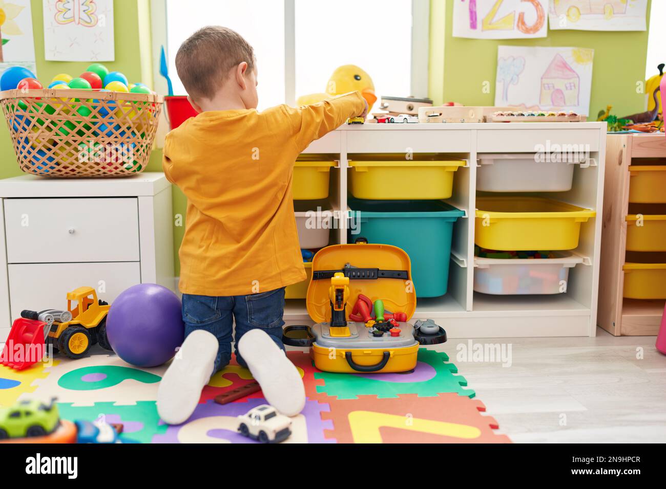 Adorable caucasian boy playing with car toy sitting on floor at ...