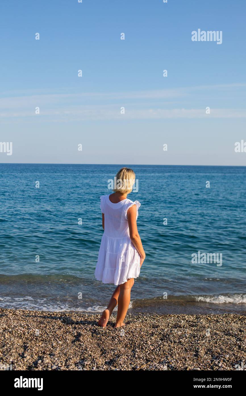 a girl on white dress walking by the sea Stock Photo - Alamy