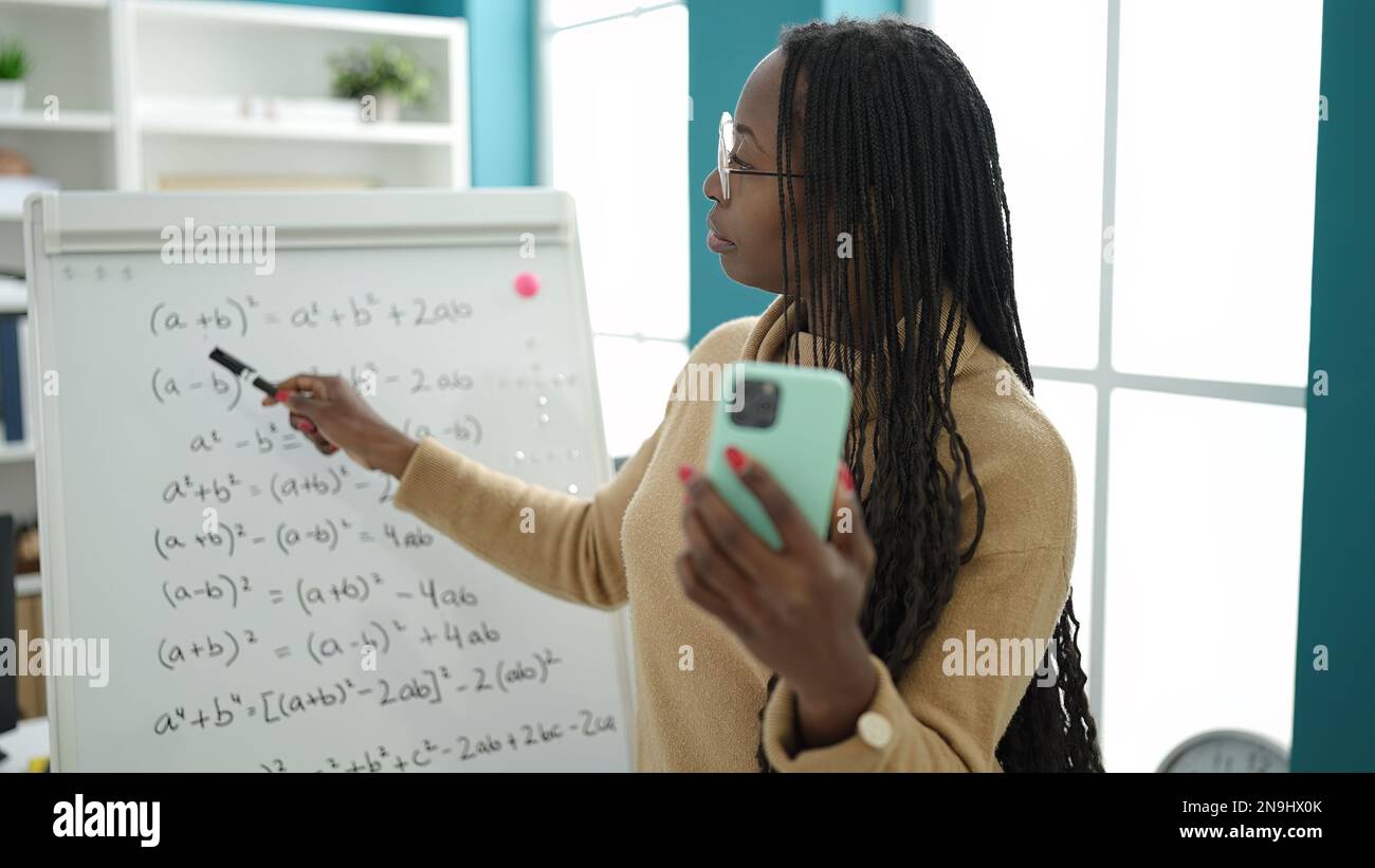 African woman recording teaching maths on magnetic board at library ...