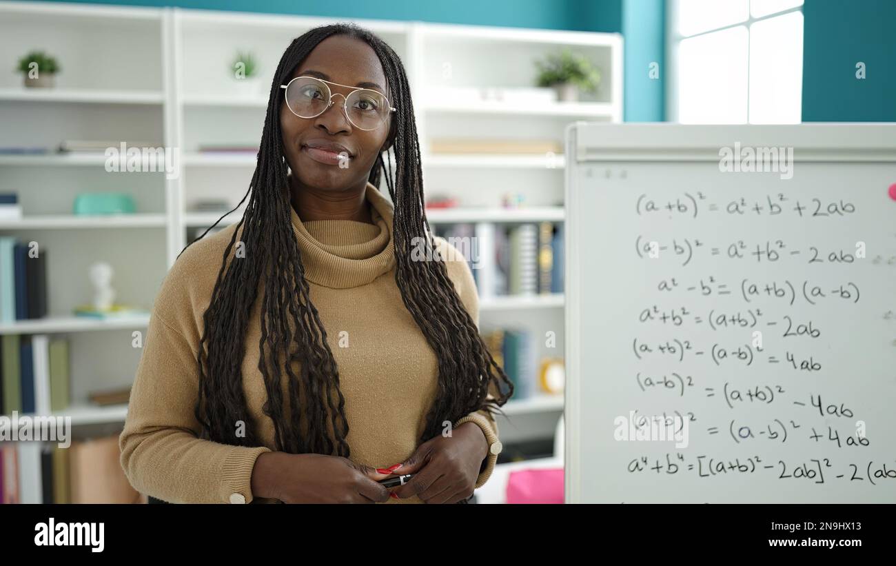 African woman smiling confident by maths magnetic board at library ...