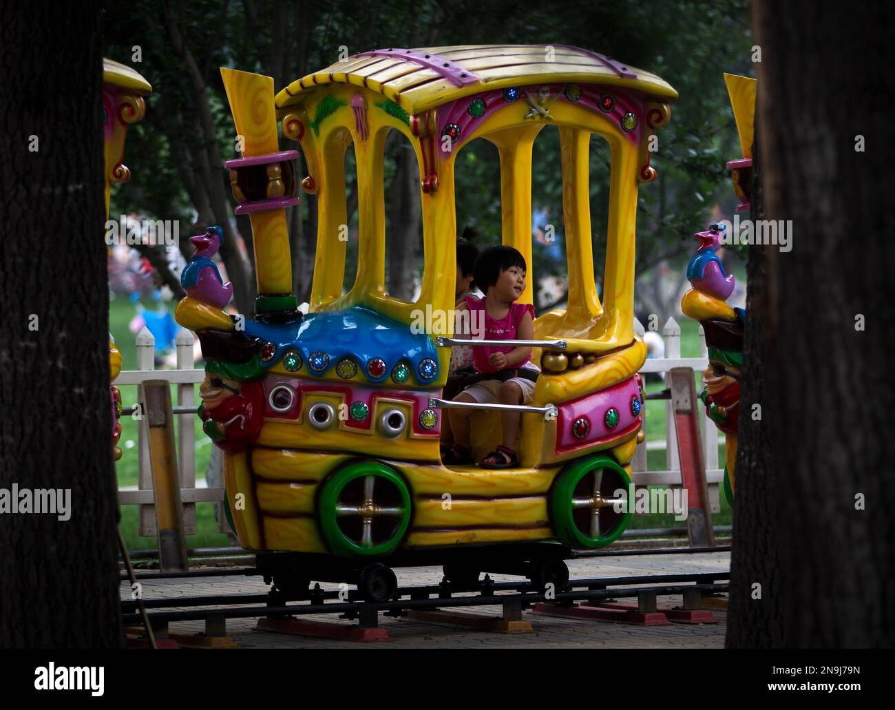 A Chinese child looks at her parent as she rides on an amusement park ...