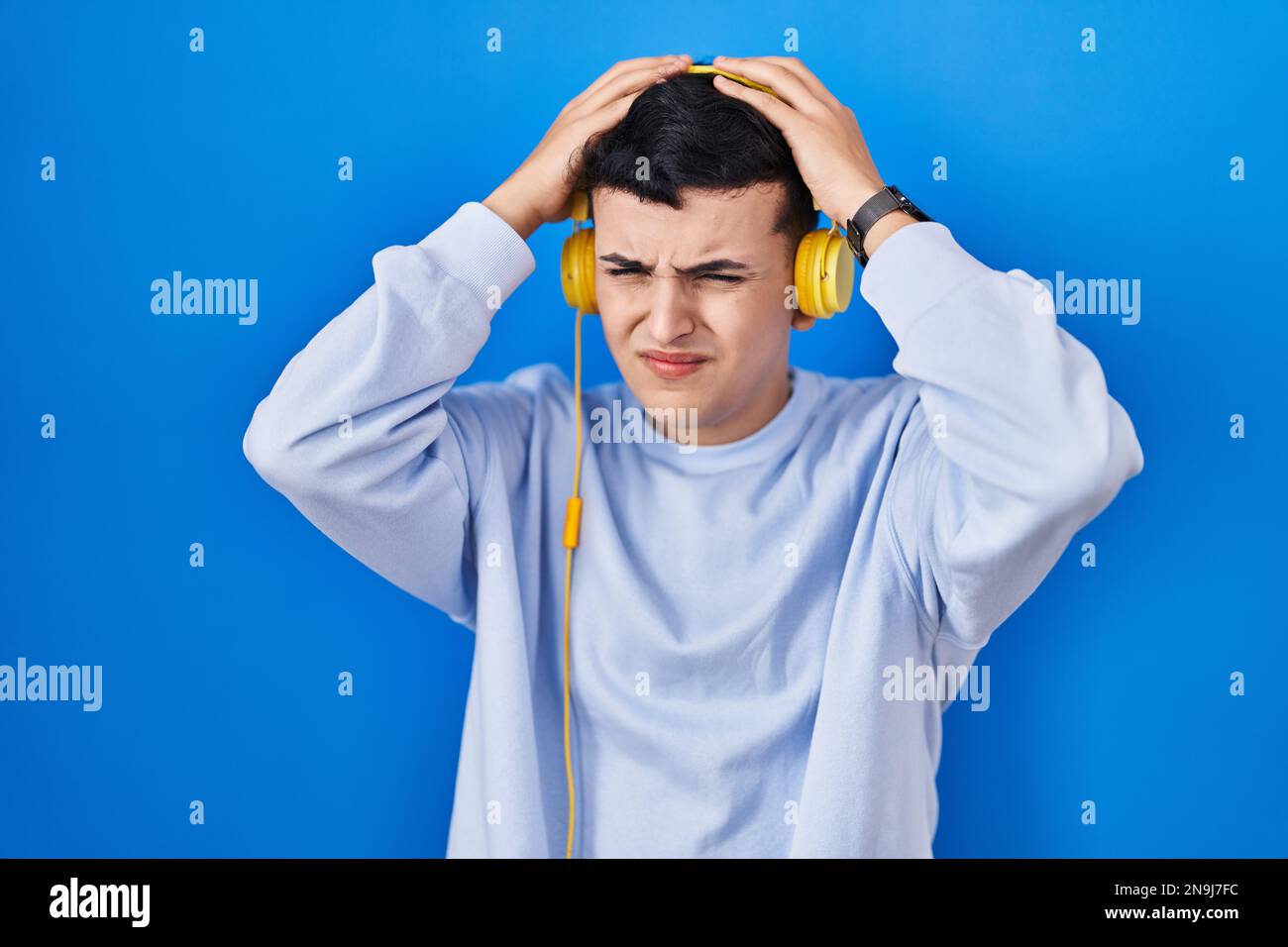 Non binary person listening to music using headphones suffering from headache desperate and