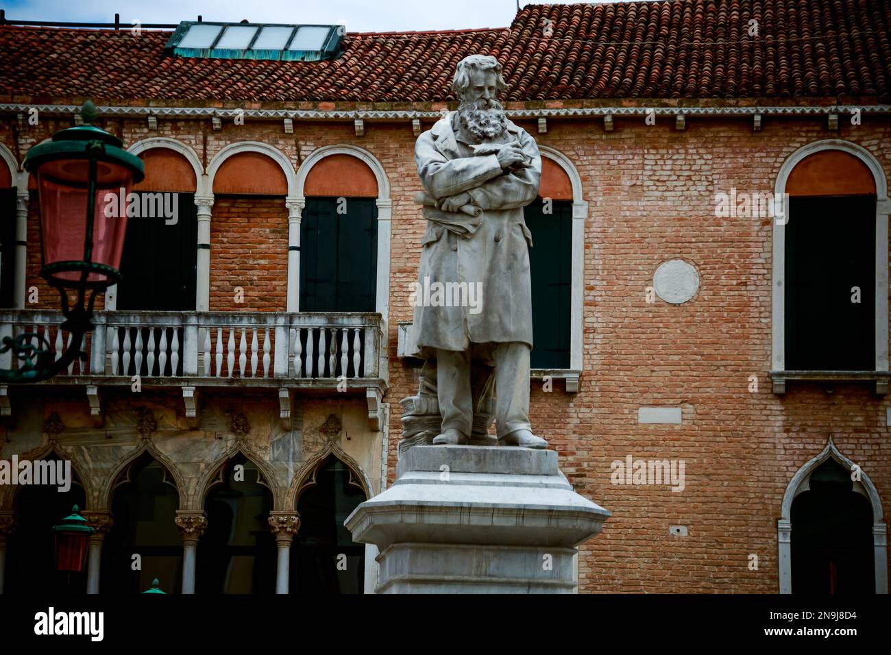 A daytime view of the statue of Niccolo Tommaseo with an old Venetian building in background, Italy Stock Photo