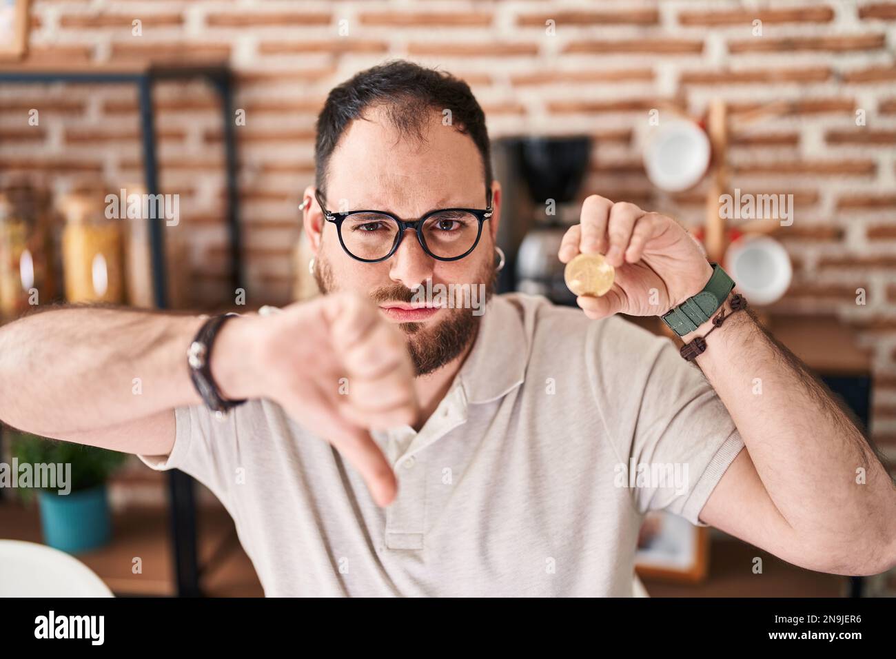 Plus size hispanic man with beard holding virtual currency bitcoin with ...