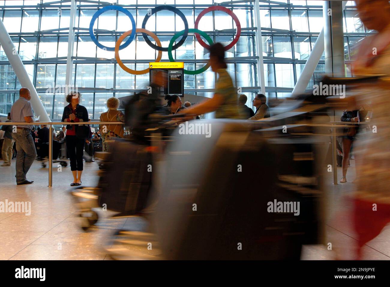 Passengers exiting the arrival terminal, pass a giant Olympic Rings ...