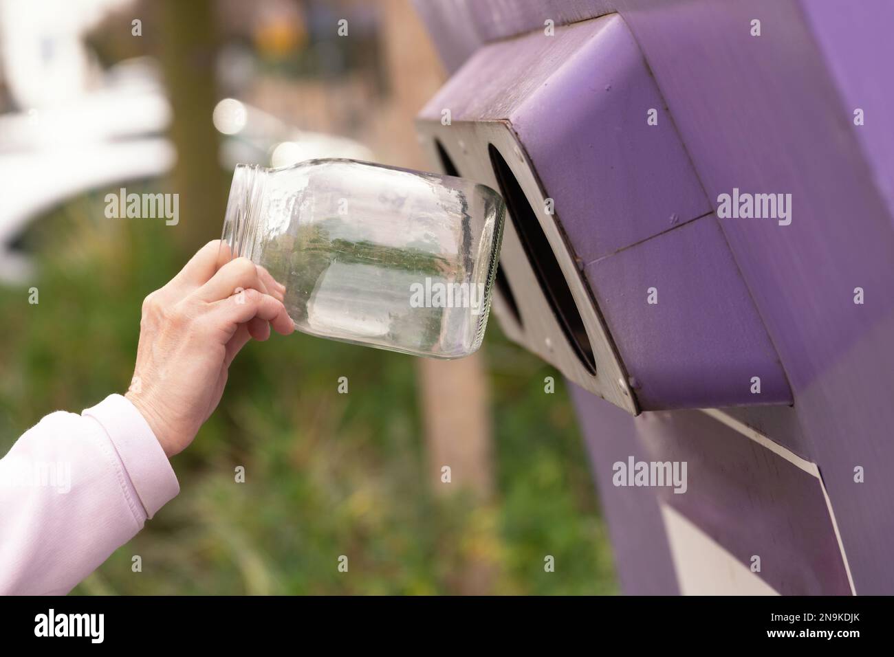 Hand throwing a glass jar into a container for separate garbage